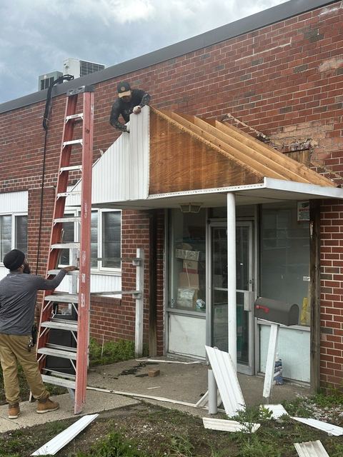 Crew removing the deteriorated front entry awning from the brick facade