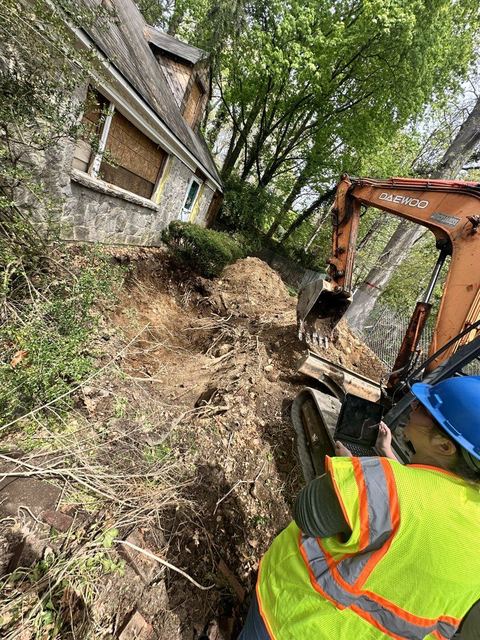 Crew member in high-visibility vest beside the excavation following tank extraction