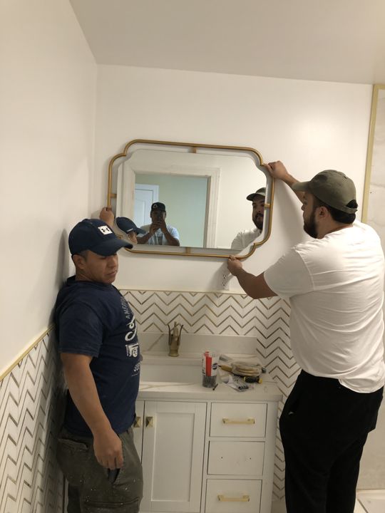 Bathroom vanity and mirror being installed.